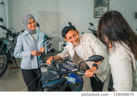 Asian man holding the handlebar of a new motorcycle with his wife 119088674