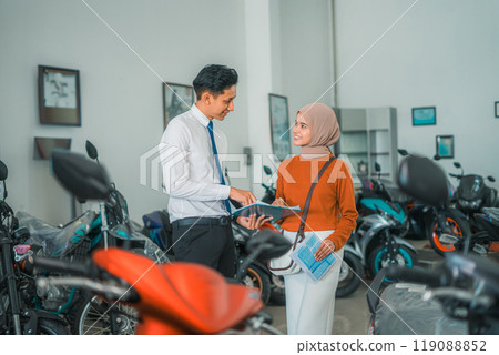 motorcycle sales man meets veiled female customer at motorcycle showroom motorcycle sales man meets veiled female customer at motorcycle showroom 119088852