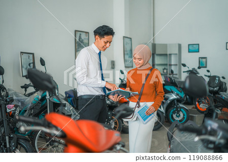 motorcycle sales man chats with a veiled female visitor 119088866