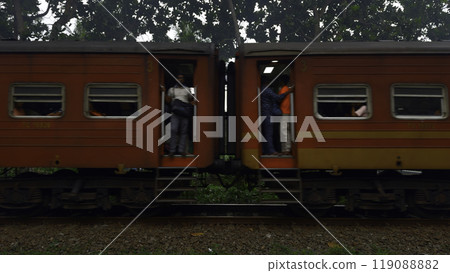 Train with people in rainforest. Action. Passing train with people looking out in tropical village. Train with passengers in tropical zone 119088882
