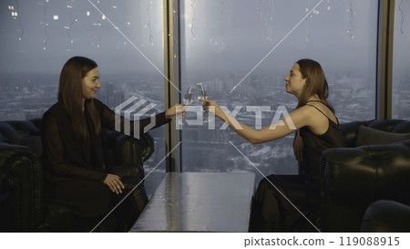 Attractive women clink glasses and drink champagne in restaurant. Media. Beautiful young women relax in champagne restaurant. Friends meet and celebrate with champagne in restaurant Attractive women clink glasses and drink champagne in restaurant. Media. Beautiful young women relax in champagne restaurant. Friends meet and celebrate with champagne in restaurant 119088915