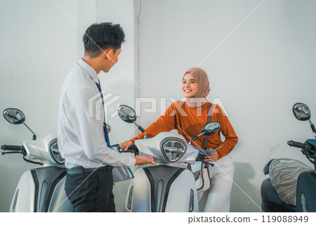 a female customer tries out a new motorcycle with a male salesperson a female customer tries out a new motorcycle with a male salesperson 119088949