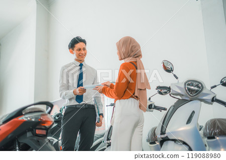 a sales man gives a brochure to a female visitor a sales man gives a brochure to a female visitor 119088980