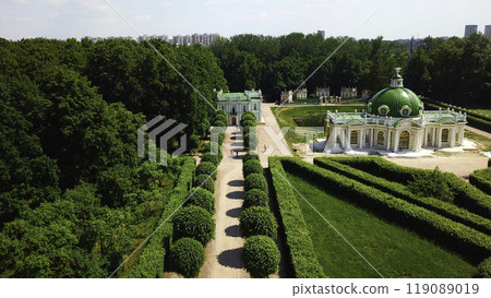 Top view of people walking on territory of palace garden. Creative. Beautiful road of palace garden with beautiful bushes and trees. Old building of royal estate with garden on sunny summer day Top view of people walking on territory of palace garden. Creative. Beautiful road of palace garden with beautiful bushes and trees. Old building of royal estate with garden on sunny summer day 119089019