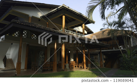Beautiful exterior of cozy villa with palm trees. Action. Beautiful villa with wooden beams in exterior. Rent villa with palm trees on vacation in tropics 119089041