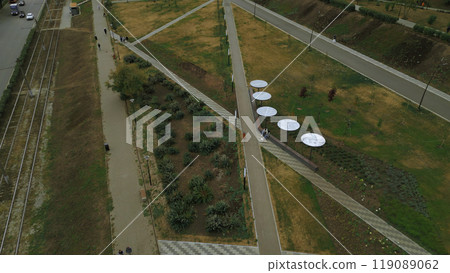 Top view of people walking in park alley in city. Clip. People walk and relax in modern city park. Landscape of city park alley with solar panels Top view of people walking in park alley in city. Clip. People walk and relax in modern city park. Landscape of city park alley with solar panels 119089062