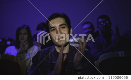 Young man is watching theatrical performance. Media. Man is watching theatrical performance in place. Spectator illuminated by spotlight at theatrical performance Young man is watching theatrical performance. Media. Man is watching theatrical performance in place. Spectator illuminated by spotlight at theatrical performance 119089066