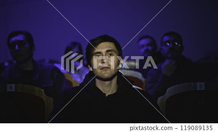 Young man is watching theatrical performance. Media. Man is watching theatrical performance in place. Spectator illuminated by spotlight at theatrical performance Young man is watching theatrical performance. Media. Man is watching theatrical performance in place. Spectator illuminated by spotlight at theatrical performance 119089135
