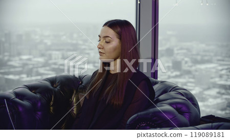 Young woman is working on laptop in restaurant. Media. Young woman is working on laptop in restaurant in background of city. Woman in lounge restaurant with laptop 119089181
