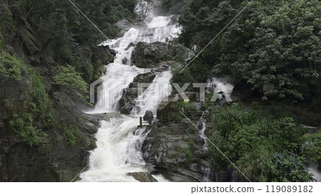 Beautiful tropical waterfall in jungle with hiking trails. Action. Cascading waterfall on rocks of rainforest. Beautiful tourist waterfall with cascades on rocks in green jungle 119089182
