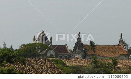 Red roofs and old buildings in southern style.l Action. Beautiful red roofs with green palm trees in southern courtyard. Sunny summer landscape of rural old village in tropical zone 119089203