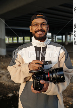 Smiling Man Holding Camera Underneath Concrete Structure 119089519