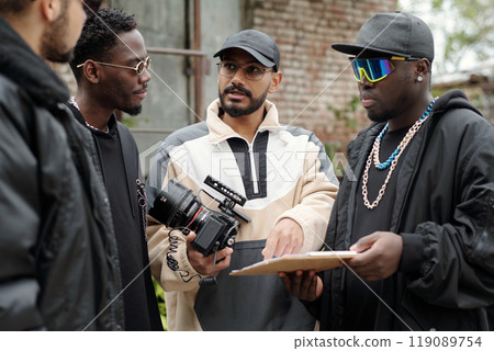 Discussing Project on Set with Film Equipment and Crew Discussing Project on Set with Film Equipment and Crew 119089754