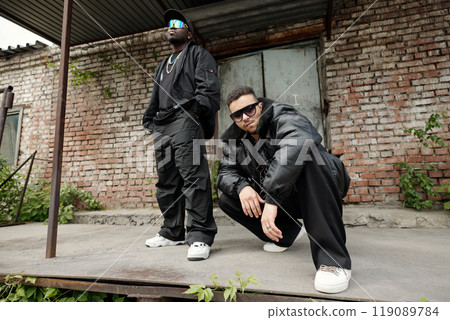 Two Men Posing Outdoors Near Brick Wall Building Entrance Two Men Posing Outdoors Near Brick Wall Building Entrance 119089784