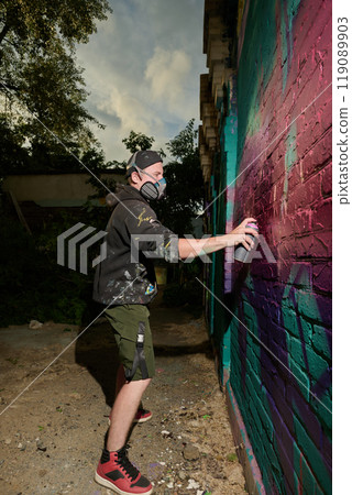 Spraying paint from dispenser on wall 119089903