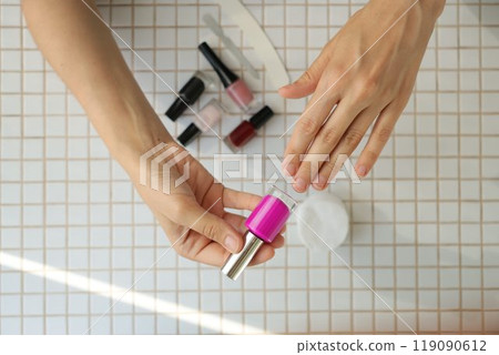 lady chooses color of nail polish. woman's hand and nail polish on table background. 119090612