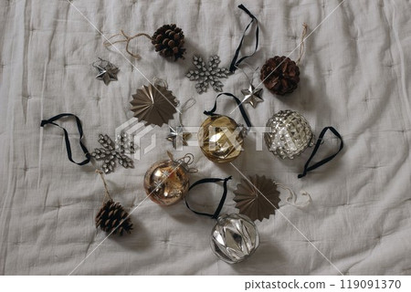 Beautiful old Christmas ornaments. Vintage glass Christmas baubles, balls. Pine cones on grey muslin blanket, throw. Decorative winter composition on table, decor. Moody festive holiday banner. 119091370