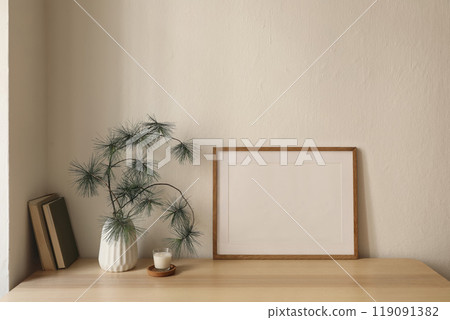 Christmas Scandinavian interior. Winter home decor. Blank horizontal wooden picture frame mockup, candle in glass on table with old books. Pine tree branches, vase. Beige wall background Christmas Scandinavian interior. Winter home decor. Blank horizontal wooden picture frame mockup, candle in glass on table with old books. Pine tree branches, vase. Beige wall background 119091382