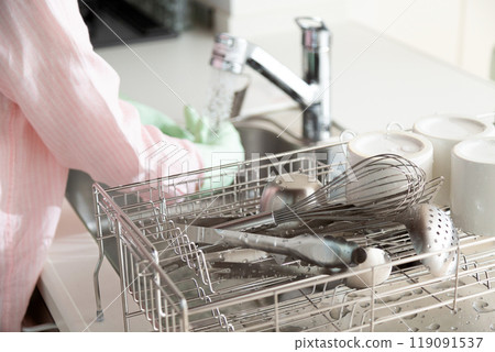 A middle-aged woman washing dishes and cookware in the kitchen 119091537