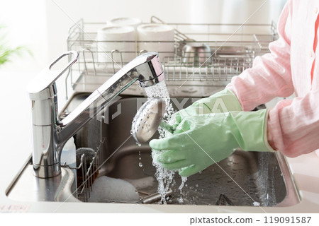 A middle-aged woman washing dishes and cookware in the kitchen 119091587