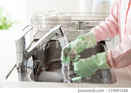 A middle-aged woman washing dishes and cookware in the kitchen 119091588