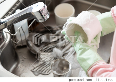 A middle-aged woman washing dishes and cookware in the kitchen A middle-aged woman washing dishes and cookware in the kitchen 119091590