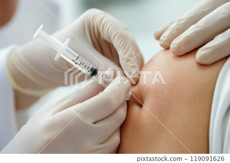doctors hand holding a medical syringe while injecting on patient skin . 119091626