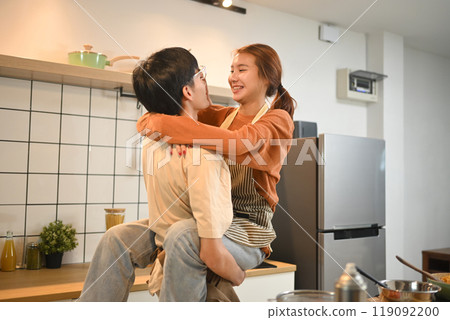 Playful young couple having fun cooking together in cozy kitchen. Love, relationships and domestic life concept Playful young couple having fun cooking together in cozy kitchen. Love, relationships and domestic life concept 119092200