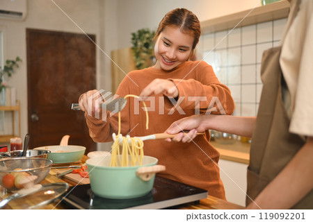 Beautiful young couple cooking together in kitchen. Relationships and domestic life concept Beautiful young couple cooking together in kitchen. Relationships and domestic life concept 119092201