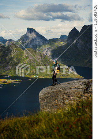A hiker on a cliff in the majestic Norwegian fjord landscape, showcasing natures beauty A hiker on a cliff in the majestic Norwegian fjord landscape, showcasing natures beauty 119092426
