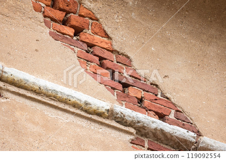 Damaged wall made of red bricks with yellow stucco, background photo 119092554