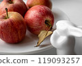 ripe red apples on white porcelain plate decorated with rabbit 119093257