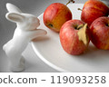 ripe red apples on white porcelain plate decorated with rabbit 119093258
