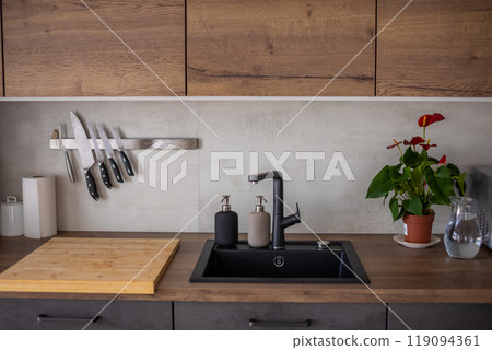 Modern kitchen in grey colors and wooden cupboards at home with kitchenware Modern kitchen in grey colors and wooden cupboards at home with kitchenware 119094361
