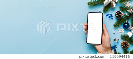 christmas mockup with space for text. christmas advertising, app template. hand holding phone with empty screen on table background. Happy New Year and Xmas Flat lay christmas mockup with space for text. christmas advertising, app template. hand holding phone with empty screen on table background. Happy New Year and Xmas Flat lay 119094416