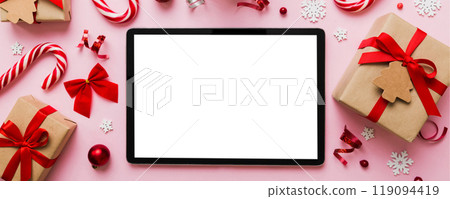 Top view of empty tablet on Christmas background made of new year decorand festive decorations. New year holiday concept. Mockup Top view of empty tablet on Christmas background made of new year decorand festive decorations. New year holiday concept. Mockup 119094419