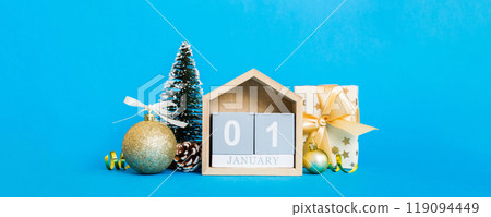 1 january. Christmas composition on colored background with a wooden calendar, with a gift box, toys, bauble copy space 1 january. Christmas composition on colored background with a wooden calendar, with a gift box, toys, bauble copy space 119094449