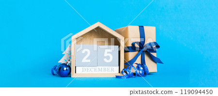 25 december. Christmas composition on colored background with a wooden calendar, with a gift box, toys, bauble copy space 25 december. Christmas composition on colored background with a wooden calendar, with a gift box, toys, bauble copy space 119094450