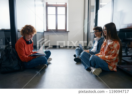 Some teenagers sitting on floor in office 119094717