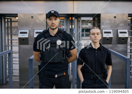 Diverse police officers patrolling and guarding entrance to public subway 119094805