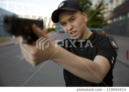 Woman patrol police officer aiming with handgun at city street 119094814