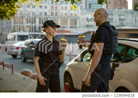 Diverse young two patrol police officers drinking coffee enjoying break rest Diverse young two patrol police officers drinking coffee enjoying break rest 119094816