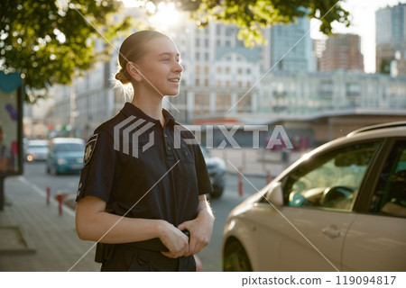 Closeup view of female patrol police officer standing on city street 119094817