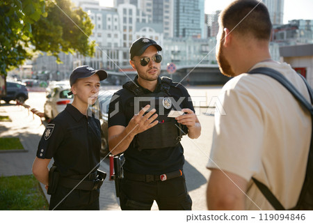 Patrol policeman and policewoman checking personal documents of citizen Patrol policeman and policewoman checking personal documents of citizen 119094846