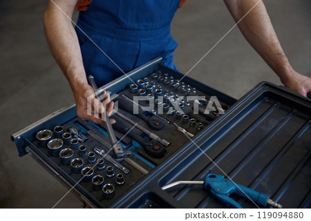 Closeup high angle view on tool box and male mechanic hands taking wrench Closeup high angle view on tool box and male mechanic hands taking wrench 119094880