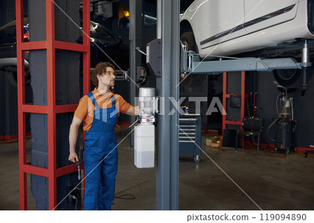 Auto service worker lifting car on elevator at repair shop 119094890