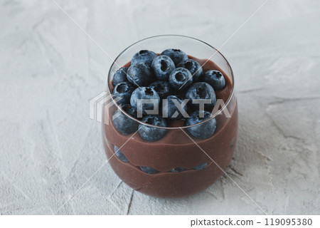 A glass of chocolate pudding topped with juicy fresh blueberries 119095380