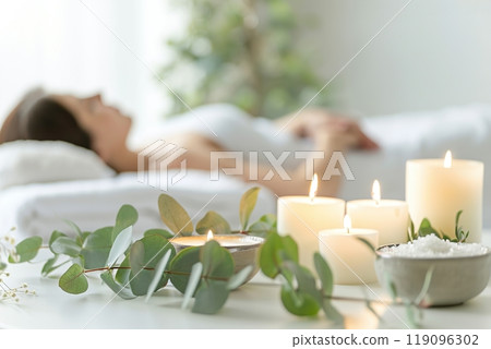 Young woman enjoying exotic massage. Relaxed girl lying on a bed. Spa items for procedures on the foreground. Candles, essential oils and sea salt. Aromatherapy. Beauty treatment and relax concept. 119096302
