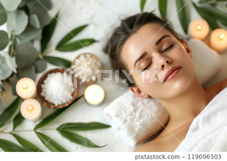 Young woman enjoying exotic massage. Relaxed girl lying on a bed. Spa items for procedures. Top view, from above. Candles, essential oils and sea salt. Aromatherapy. Beauty treatment and relax concept Young woman enjoying exotic massage. Relaxed girl lying on a bed. Spa items for procedures. Top view, from above. Candles, essential oils and sea salt. Aromatherapy. Beauty treatment and relax concept 119096303
