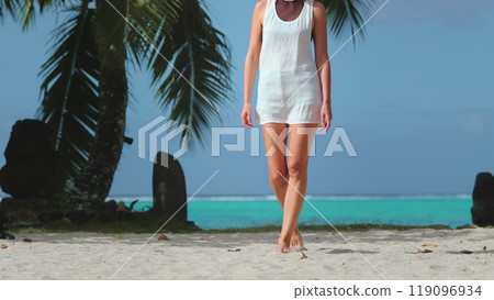 Woman barefoot walking tropical sand beach. Slim girl in white shirt relaxes outdoor, lifestyle travel on summer holiday island vacation. Sunny day, blue sky, turquoise water, palm tree. Slow 119096934